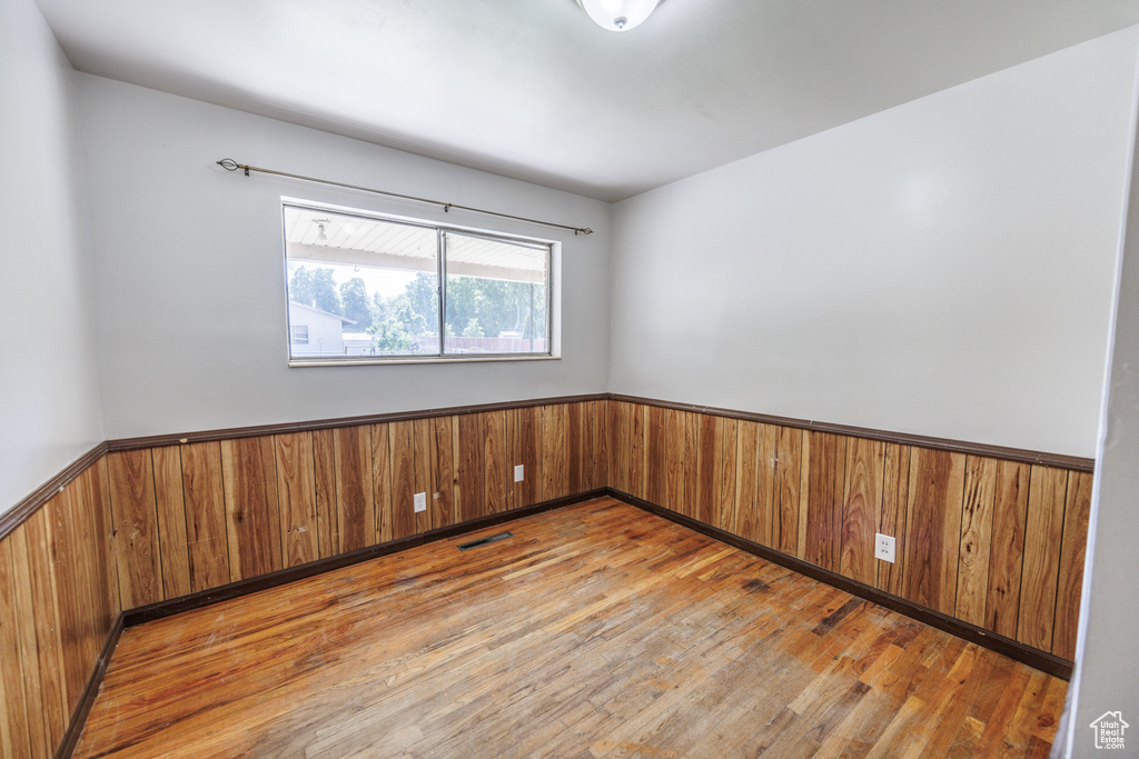 Empty room featuring wainscoting, wood finished floors, and wooden walls