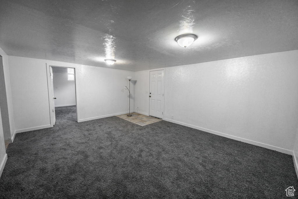 Finished below grade area featuring a textured ceiling, carpet, and baseboards