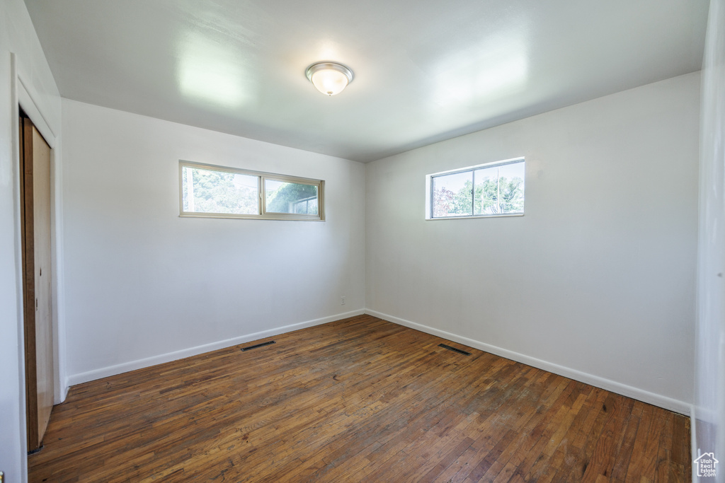 Unfurnished room with plenty of natural light, baseboards, and dark wood-style flooring