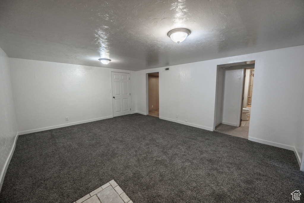 Empty room featuring baseboards, carpet flooring, and a textured ceiling