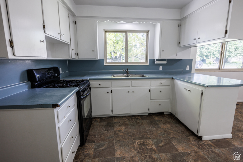 Kitchen featuring black range with gas cooktop, a sink, healthy amount of natural light, and stone finish flooring