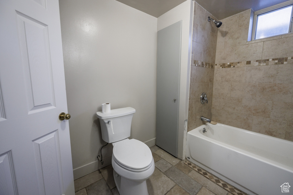 Full bath featuring toilet, shower / washtub combination, and baseboards