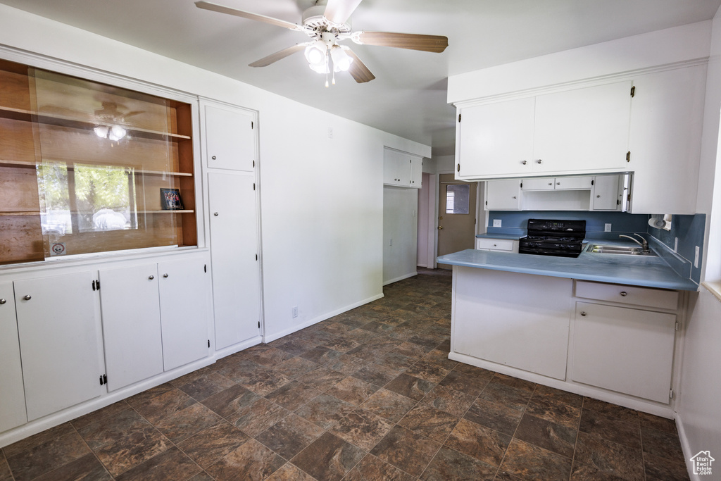 Kitchen with black gas range, a sink, a ceiling fan, and white cabinets