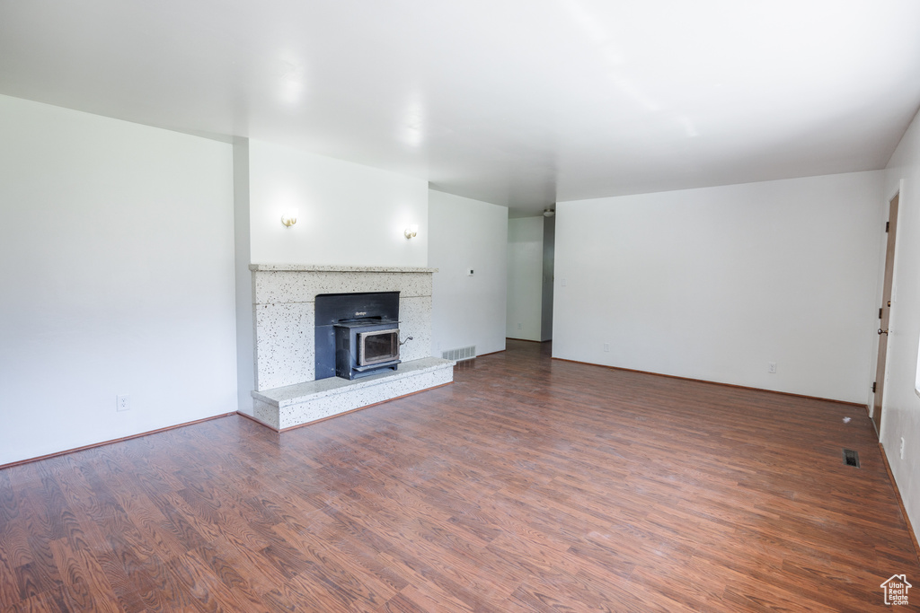 Unfurnished living room featuring wood finished floors and a wood stove