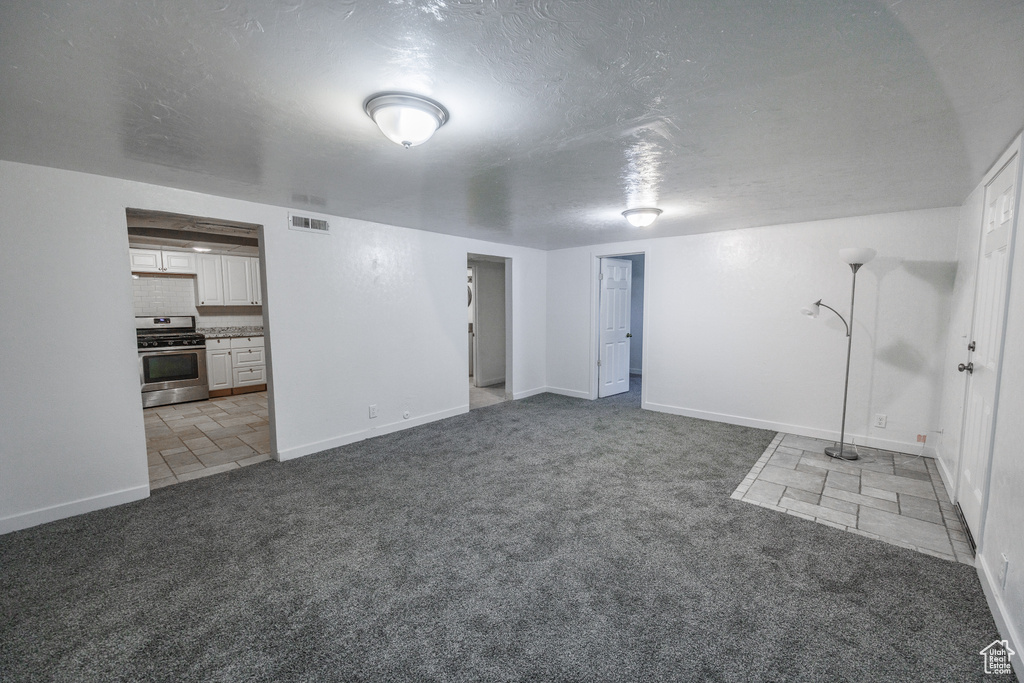Finished below grade area with carpet, baseboards, and a textured ceiling