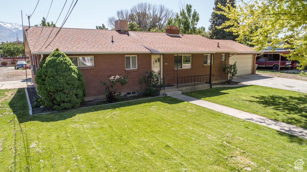 Ranch-style home with driveway, brick siding, a garage, a front lawn, and a chimney