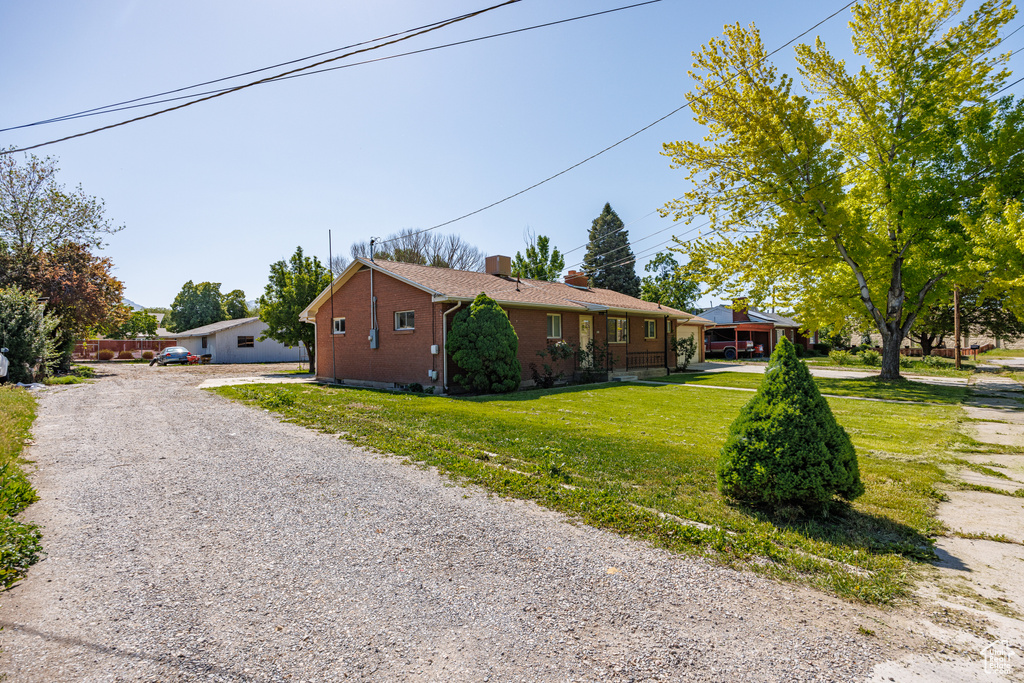 View of side of property with brick siding, a lawn, driveway, and a chimney