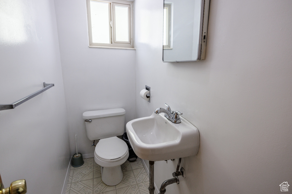 Half bath featuring toilet, a sink, and tile patterned flooring