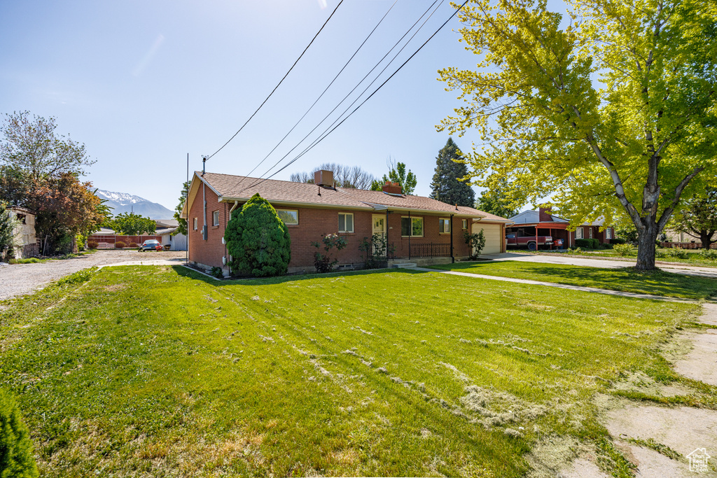 View of front facade with driveway, an attached garage, a chimney, brick siding, and a mountain view