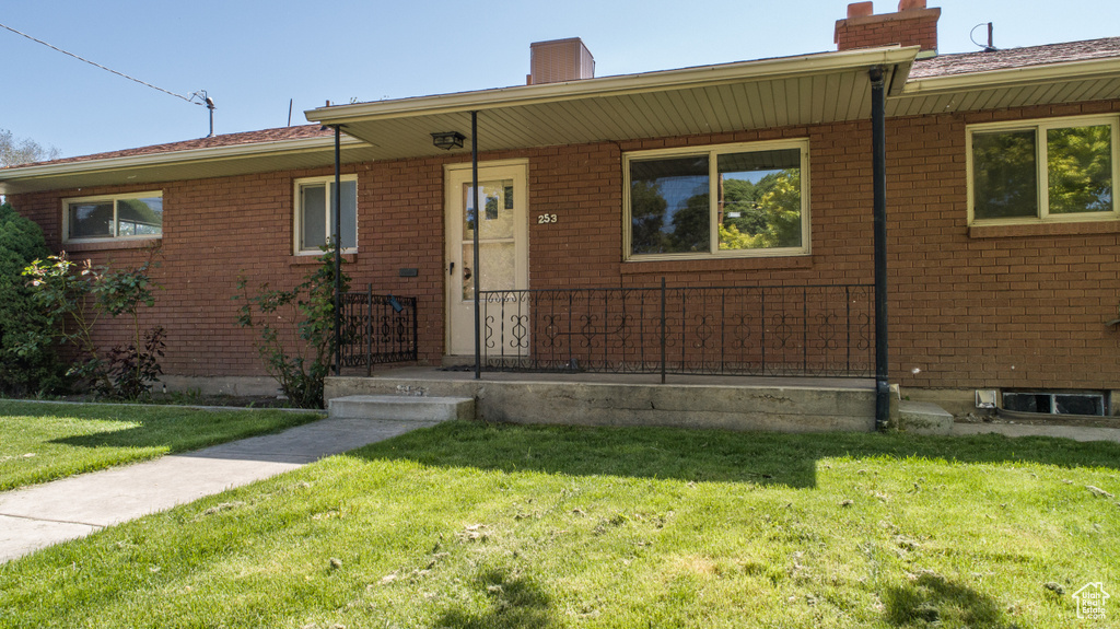 Ranch-style house with a chimney, a front yard, and brick siding