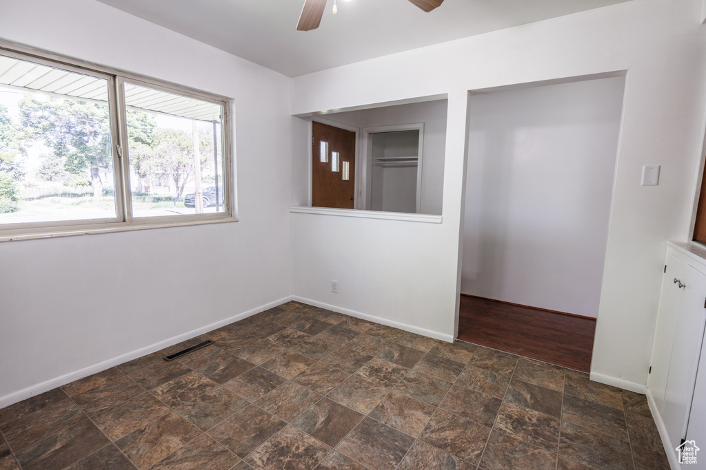 Empty room with stone finish flooring, a ceiling fan, and baseboards
