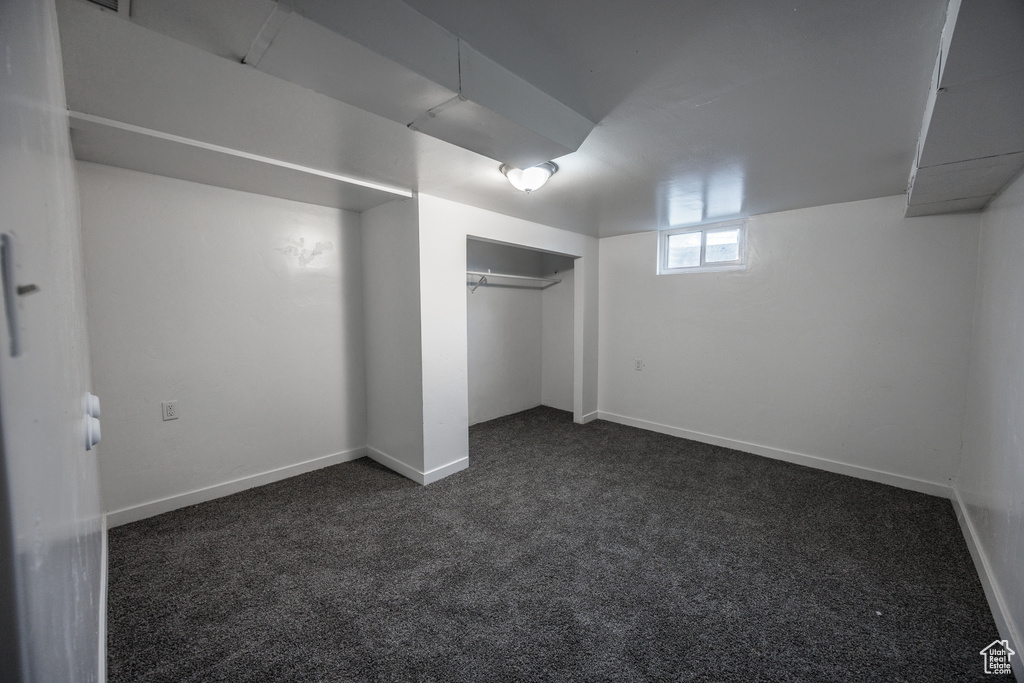Unfurnished bedroom featuring dark colored carpet, baseboards, and a closet