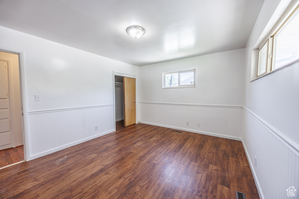 Unfurnished bedroom featuring wainscoting, wood finished floors, and a closet