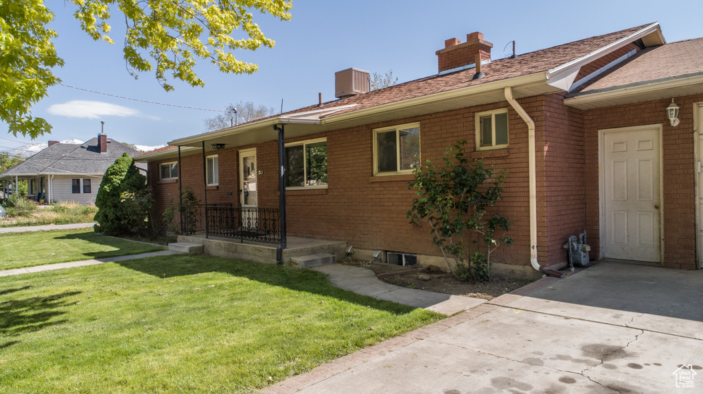 View of front of property featuring a chimney, a front yard, and brick siding