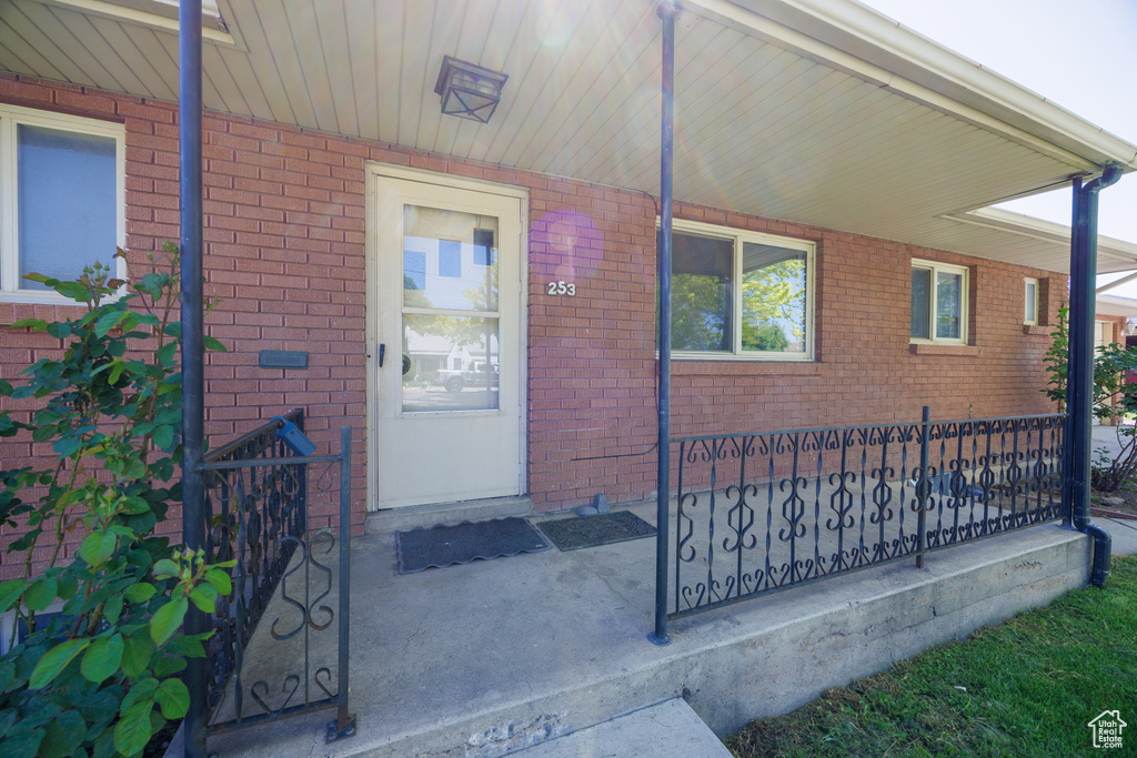 View of exterior entry featuring covered porch and brick siding