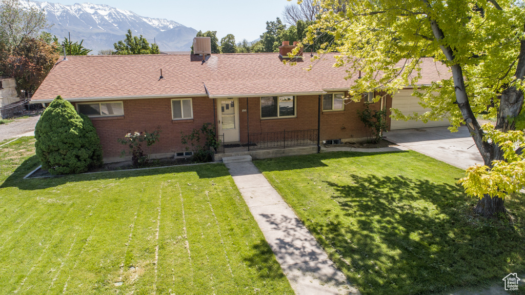 Single story home featuring a mountain view, brick siding, driveway, and a front yard