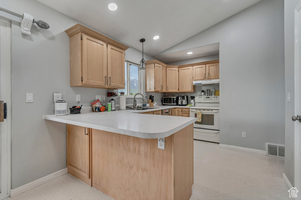 Kitchen featuring white electric stove, stainless steel microwave, a peninsula, light flooring, and light countertops