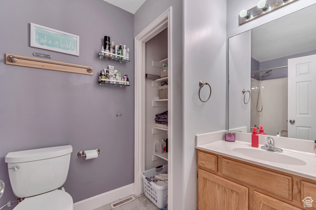 Bathroom with toilet, vanity, baseboards, and a shower