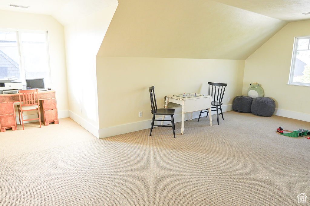 Carpeted office space featuring vaulted ceiling and baseboards
