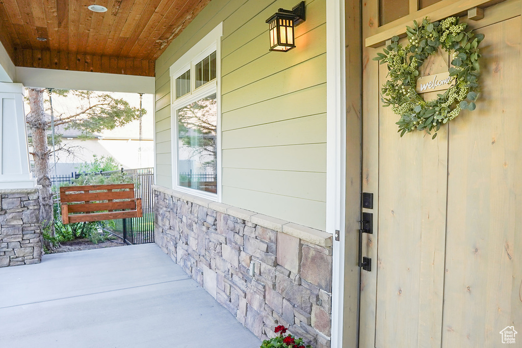 View of exterior entry featuring covered porch and stone siding