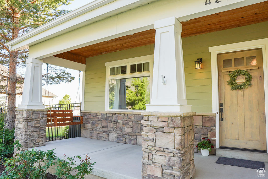 View of exterior entry featuring covered porch and stone siding