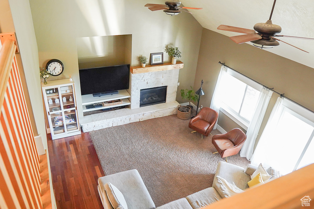 Living area featuring ceiling fan, vaulted ceiling, a glass covered fireplace, and wood finished floors