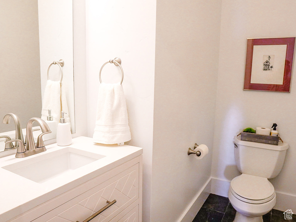 Bathroom featuring toilet, vanity, and baseboards
