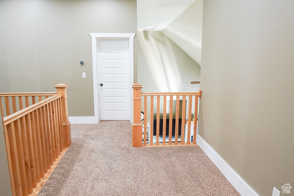 Hallway featuring an upstairs landing, carpet floors, lofted ceiling, and baseboards