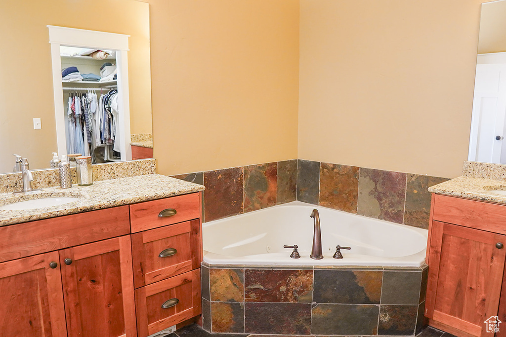 Full bath with vanity, a garden tub, and a walk in closet
