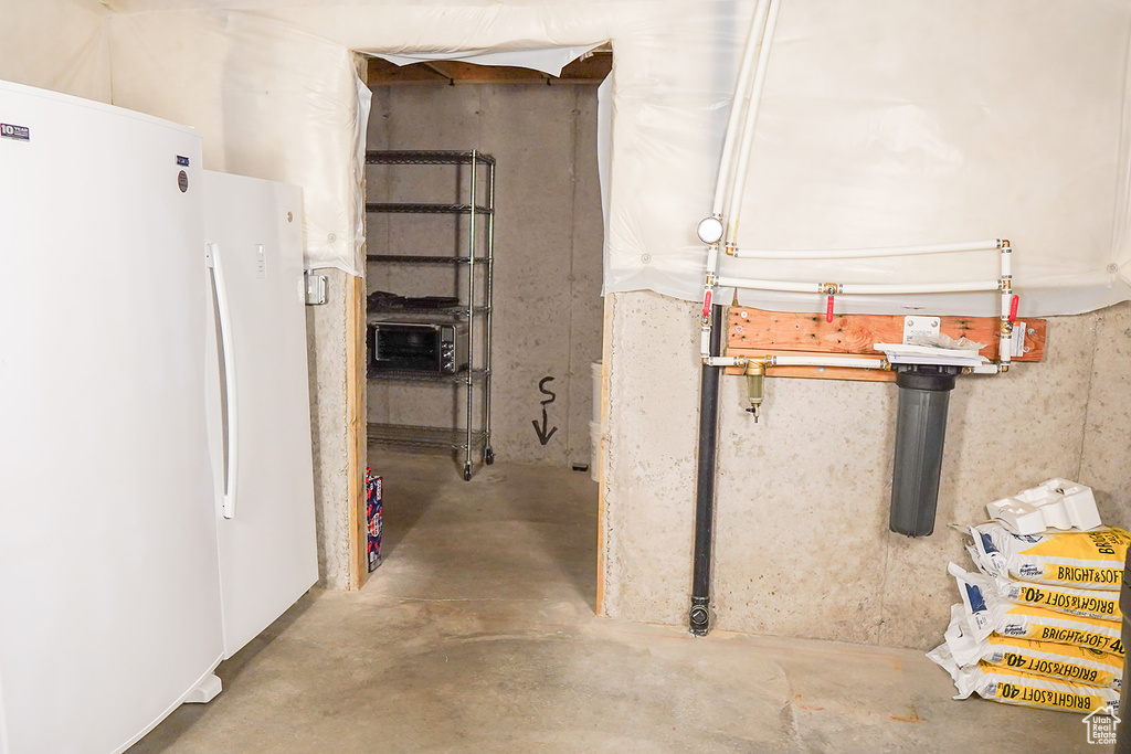 Unfinished basement with freestanding refrigerator
