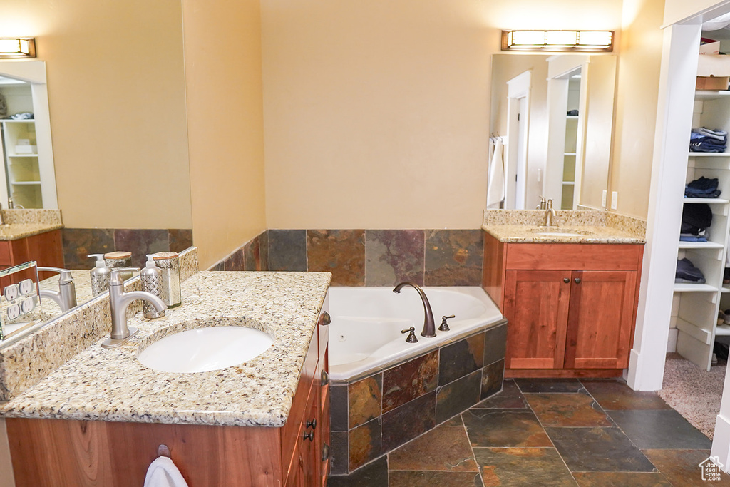 Bathroom with stone tile floors, two vanities, and a jetted tub