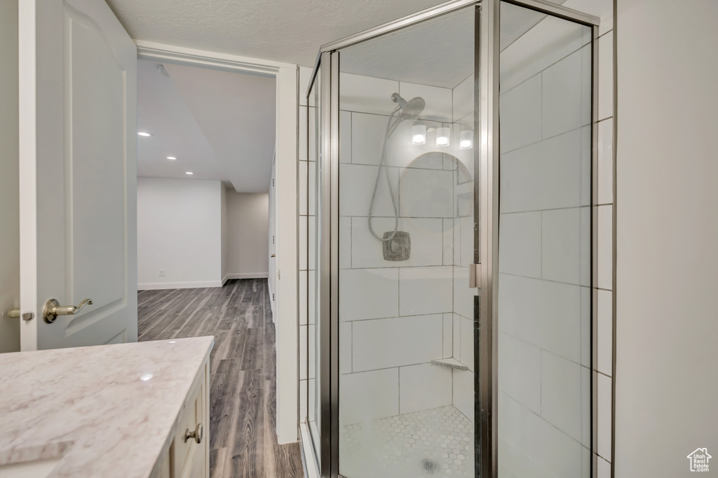 Bathroom featuring wood finished floors, a shower stall, vanity, baseboards, and recessed lighting