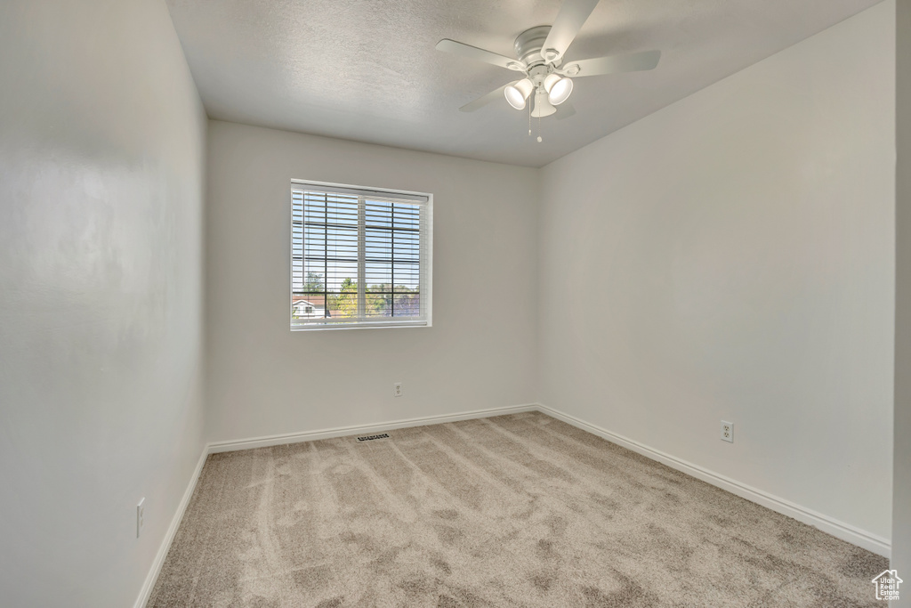Spare room featuring carpet, baseboards, and ceiling fan
