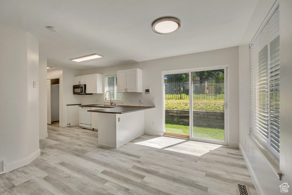 Kitchen featuring dark countertops, white cabinets, light wood finished floors, and baseboards