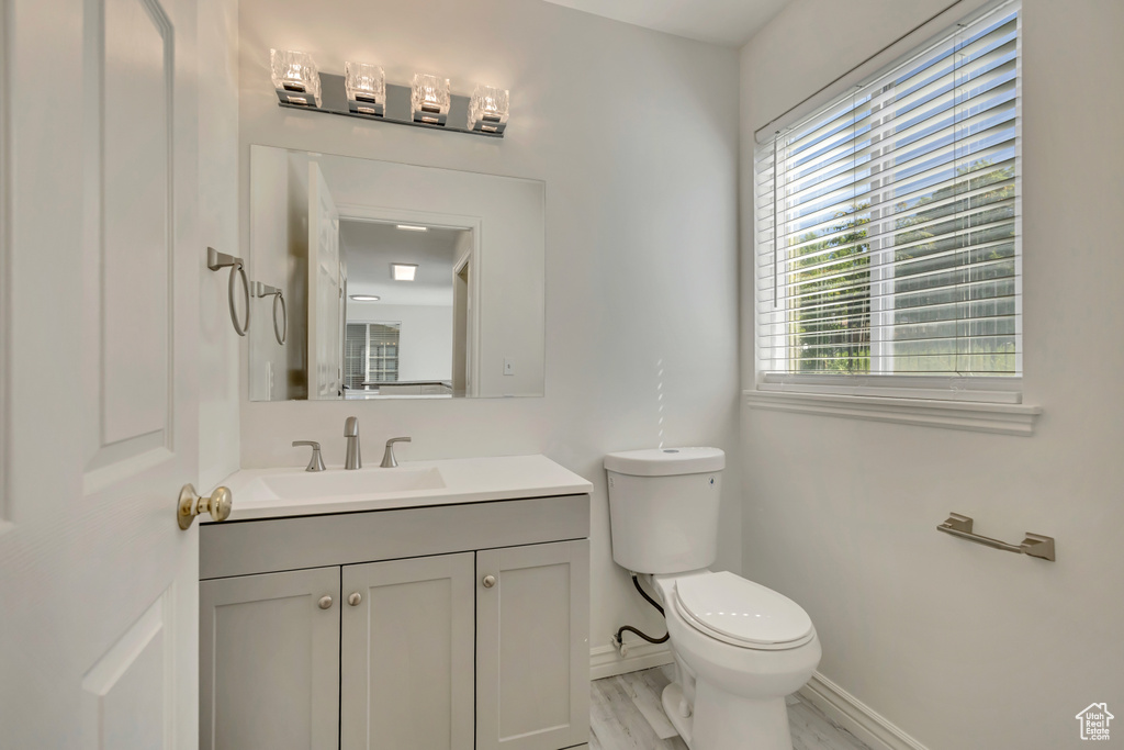 Half bath featuring baseboards, healthy amount of natural light, toilet, and vanity