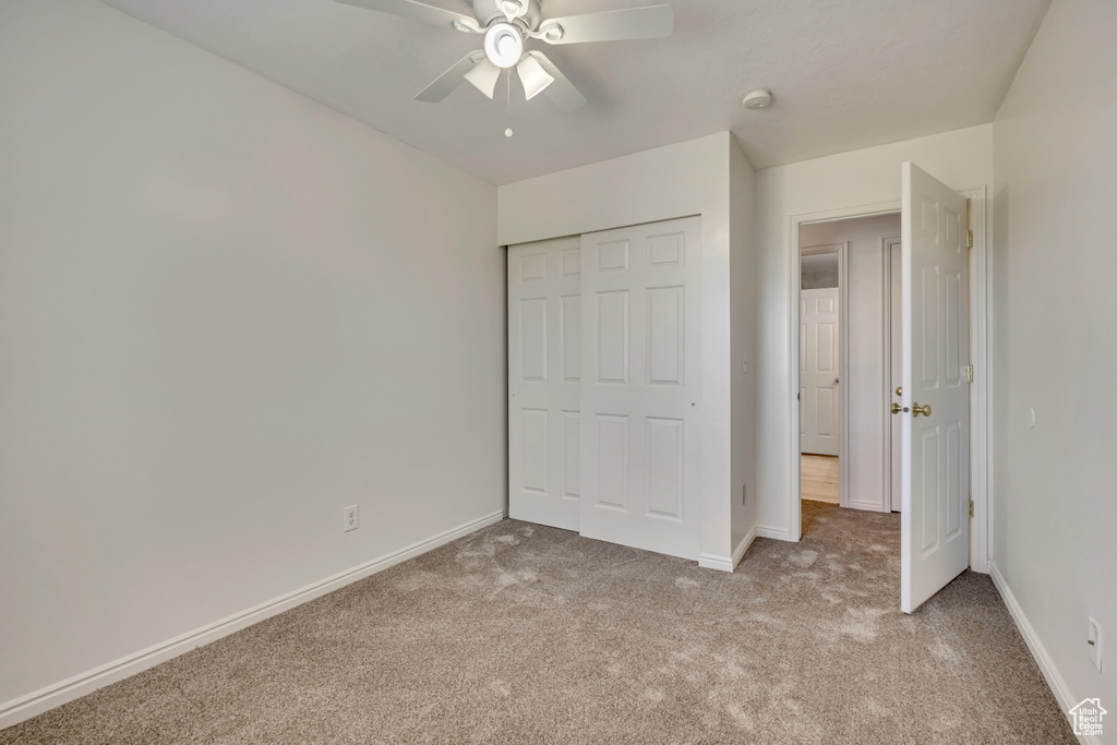 Unfurnished bedroom featuring carpet floors, a closet, baseboards, and ceiling fan