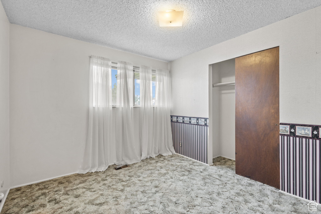 Unfurnished bedroom with carpet flooring, a closet, and a textured ceiling