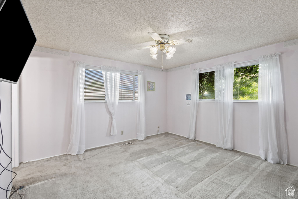 Unfurnished room with light carpet, a ceiling fan, and a textured ceiling