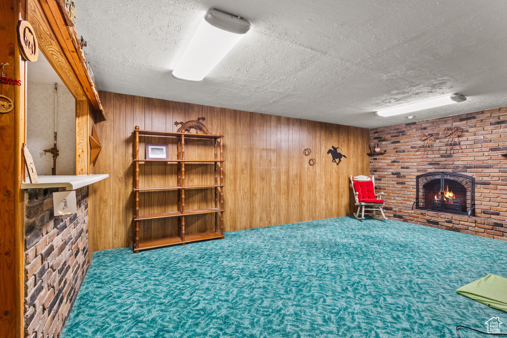 Finished below grade area featuring a fireplace, a textured ceiling, wood walls, and carpet flooring
