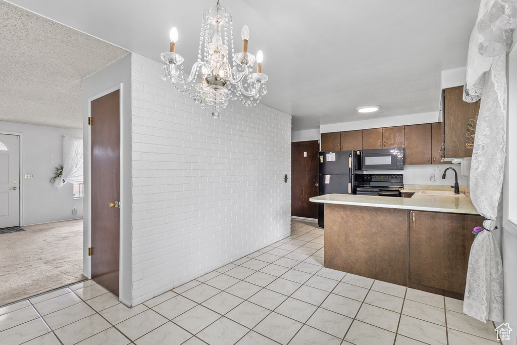 Kitchen with black appliances, light tile patterned floors, light countertops, a sink, and a chandelier