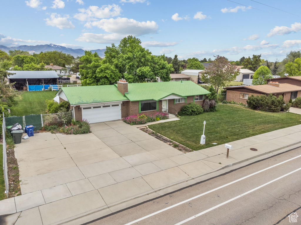 Ranch-style home featuring an attached garage, a chimney, brick siding, concrete driveway, and a mountain view