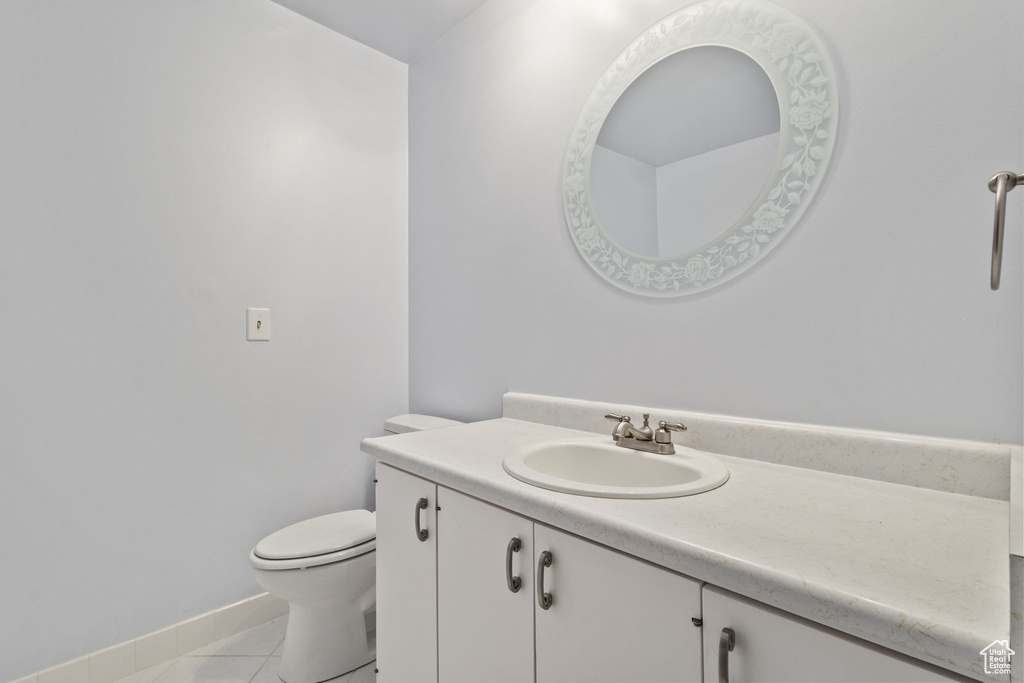 Bathroom featuring vanity, toilet, baseboards, and tile patterned flooring