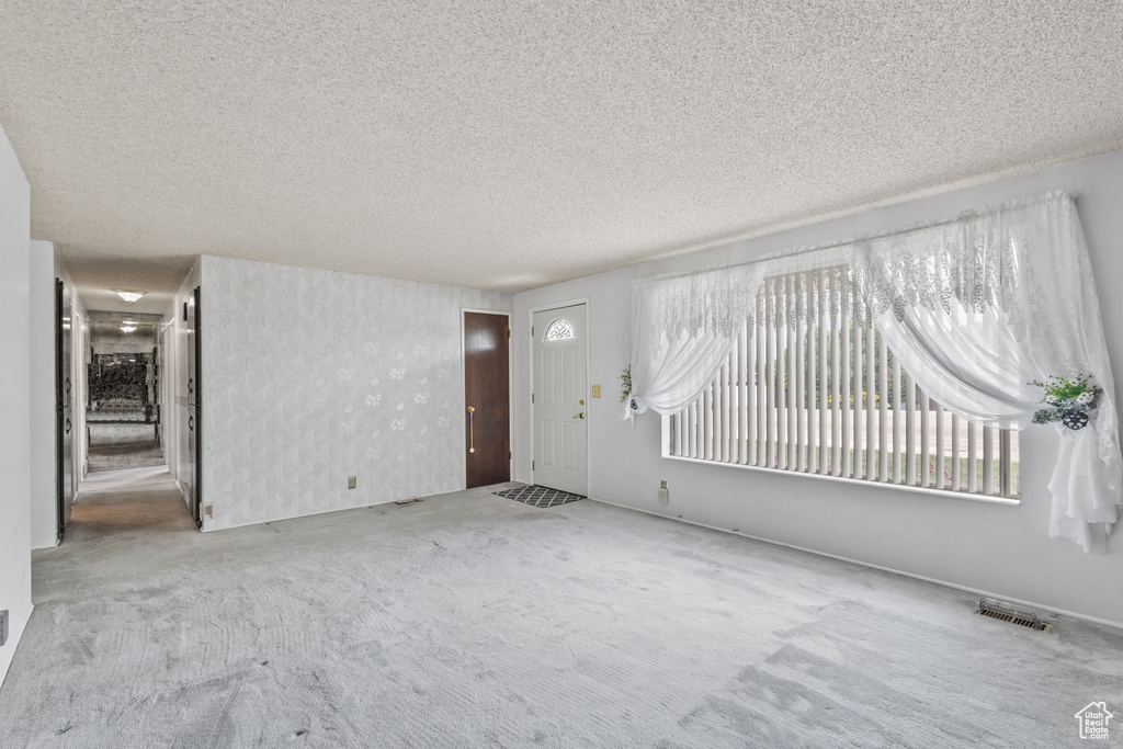 Entrance foyer with carpet flooring and a textured ceiling