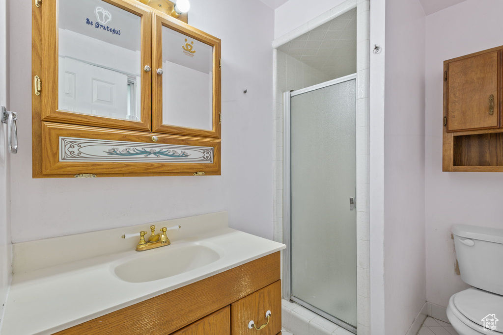 Full bathroom with toilet, vanity, a stall shower, and tile patterned floors