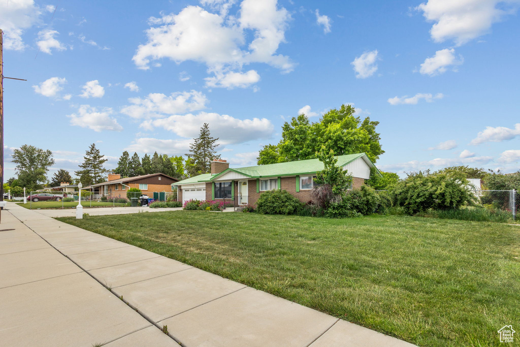 Ranch-style house featuring a garage, concrete driveway, a chimney, and brick siding