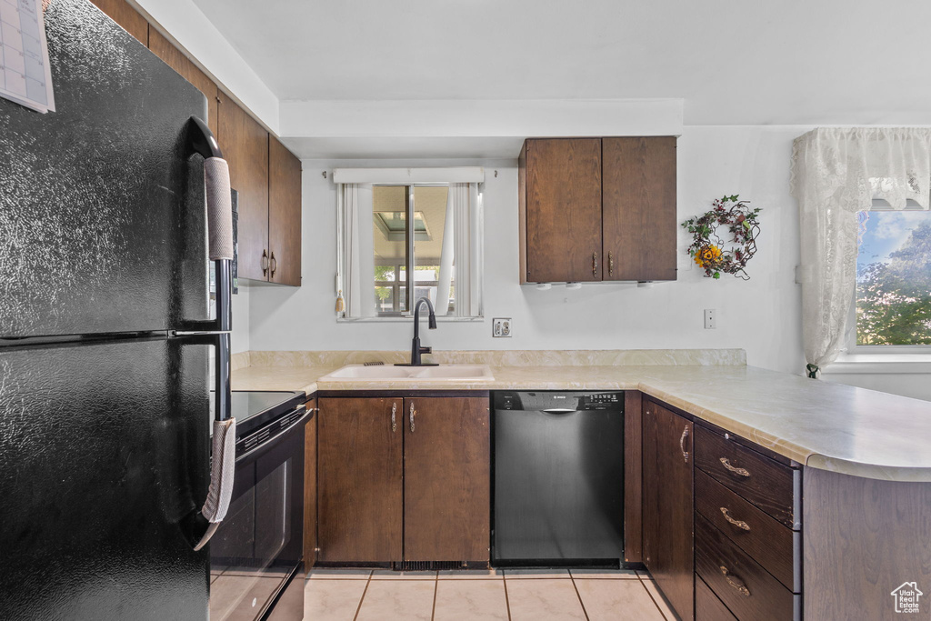 Kitchen featuring black appliances, a sink, light countertops, and light tile patterned flooring