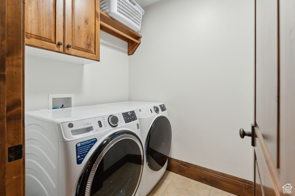 Washroom with washing machine and clothes dryer, baseboards, light tile patterned floors, and cabinet space