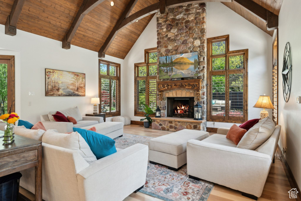 Living room featuring wood finished floors, wooden ceiling with exposed beams, a fireplace, plenty of natural light, and high vaulted ceiling