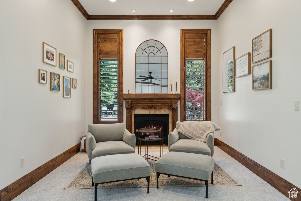 Sitting room featuring wood finished floors, baseboards, a lit fireplace, crown molding, and recessed lighting
