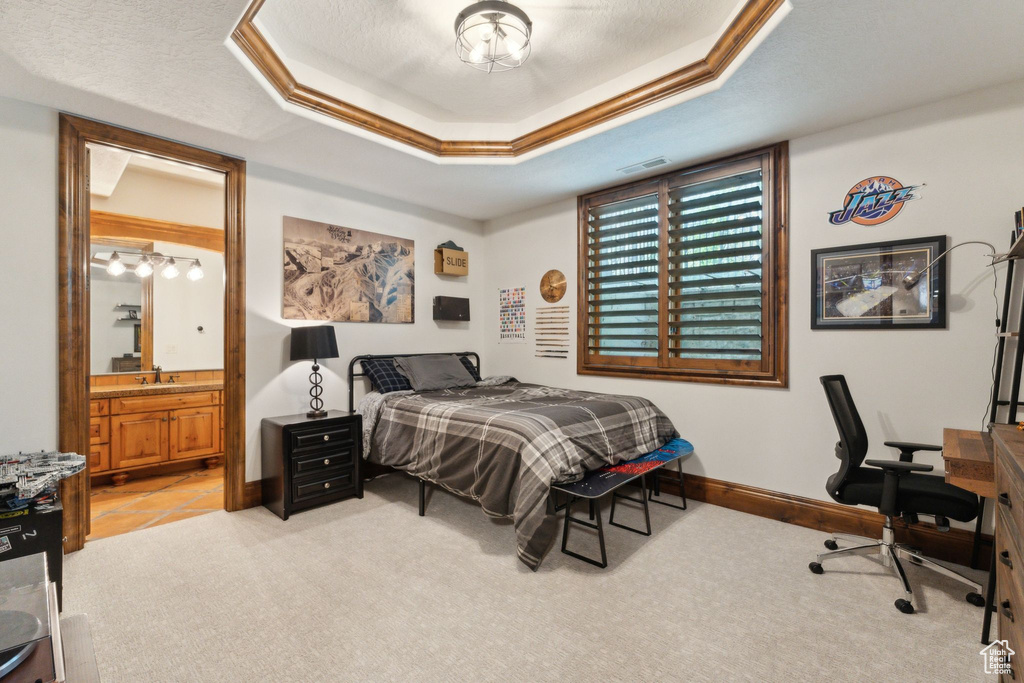 Bedroom featuring light colored carpet, ensuite bath, baseboards, an office area, and a sink
